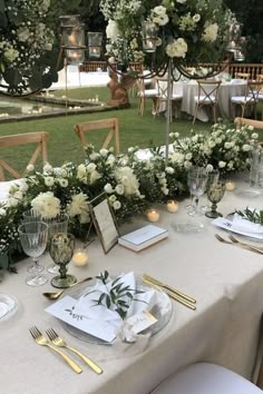 the table is set with white flowers and greenery