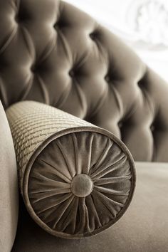 an upholstered couch with a round pillow on it's back and side