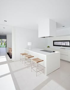 an image of a kitchen with white cabinets and stools on the counter top in front of a window