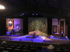 an empty stage with blue lighting and chairs