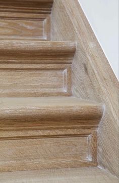 close up view of wooden stairs and handrails with white walls in the background