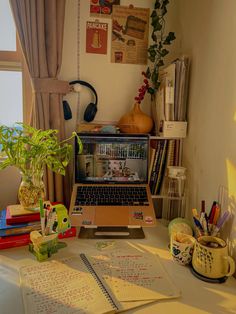 an open laptop computer sitting on top of a desk next to books and other items