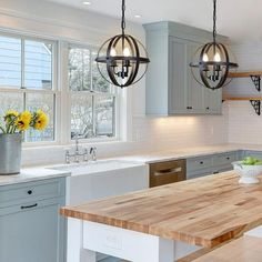 a kitchen with wooden counter tops and hanging lights over the island in front of the sink