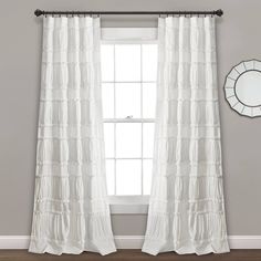 a white curtain hanging in front of a window with a mirror on the wall next to it