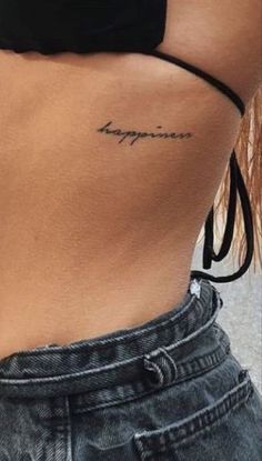 a woman's stomach with the word happiness tattooed on it