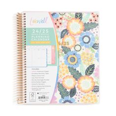 a spiral bound planner with flowers and leaves on the cover, in front of a white background