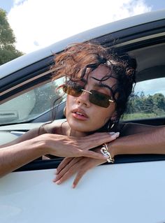 a woman in sunglasses leaning out the window of a car