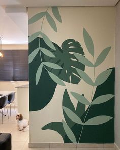 a dog is standing in front of a wall with leaves painted on it and a dining room table next to it