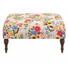 the footstool is covered with colorful flowers and wooden legs, along with a white background