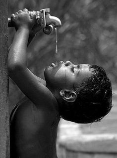 a young boy drinking water from a faucet attached to a wall with the caption save water save life