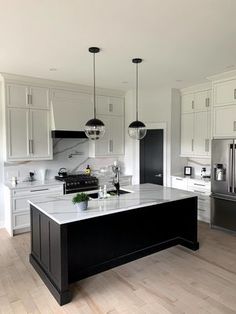 a large kitchen with white cabinets and black island