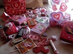 a pile of valentine's day candy and candies on the floor next to a bag