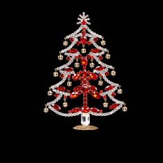 a red and white christmas tree made out of glass beads on a black background with gold accents