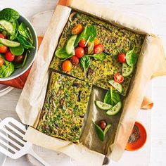 a pan filled with spinach, tomatoes and cucumbers next to a bowl of salad