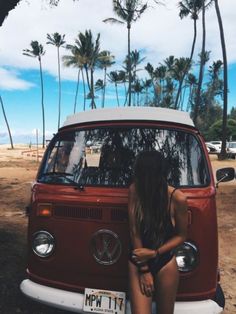 a woman sitting on the hood of a vw bus in front of palm trees