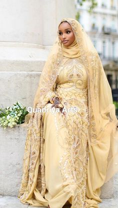 a woman in a yellow dress and head scarf is posing for the camera with her hands on her hips