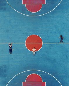 two men are playing basketball on a blue court with red and white circles in the middle