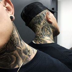 a man with tattoos and piercings on his neck is looking at another man's face