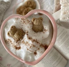 two small teddy bears are in a heart shaped cup filled with marshmallows