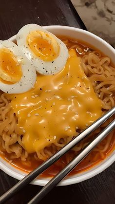 a bowl filled with noodles and topped with two hard boiled eggs on top of them