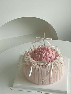 a cake with pink and white frosting in a basket on top of a table