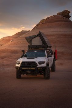 a white truck with its hood open in the desert