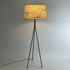 a floor lamp with a yellow shade on the base and a black metal tripod