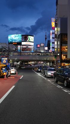 cars are parked on the street in front of tall buildings at night with city lights