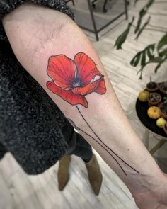 a woman's arm with a red flower tattoo on it