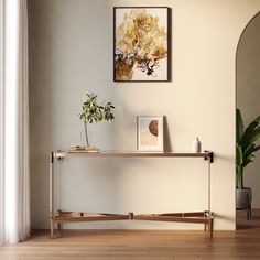 a living room with a mirror, plant and framed art on the wall above it