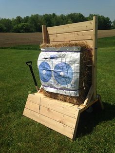 a wooden cart with hay and a shovel on it in the grass near a field