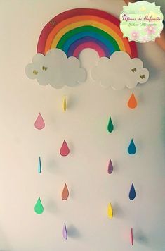 a child's room with a rainbow and clouds hanging from the wall above it