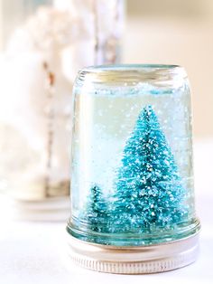 there is a small glass jar with a snow scene in it on top of a table