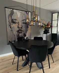 a dining room table with black chairs and a painting on the wall