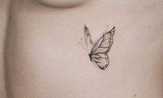 a small butterfly tattoo on the side of a woman's stomach is shown in black and white