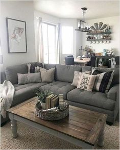 a living room with gray couches and pillows on the coffee table in front of it