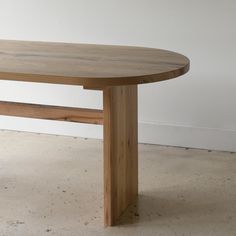 a wooden table sitting on top of a floor next to a white wall in an empty room