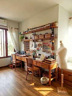 a wooden desk sitting next to a window filled with lots of crafting supplies on top of shelves