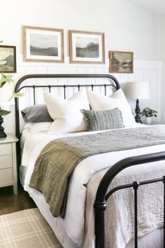 a bed with white linens and pillows in a small room next to two pictures on the wall