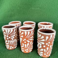 four orange and white vases sitting next to each other on a green tablecloth