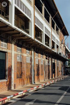 an empty street in front of a building with wooden doors on the sides and windows