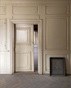 an empty room with two doors and a framed photo on the floor next to it