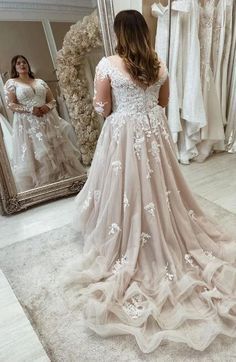 a woman is looking at her wedding dress in the mirror