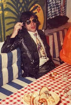 a man sitting at a table talking on a cell phone while wearing a suit and tie