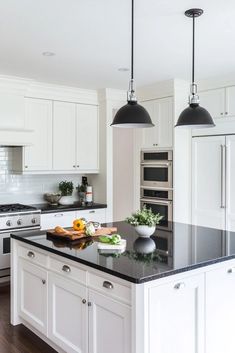 a large kitchen with white cabinets and black counter tops, along with an island in the middle