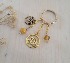 a gold keychain with two charms attached to it and a flower charm hanging from the front