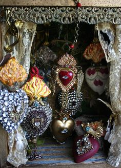 an assortment of heart shaped ornaments in a display case with laces and beadwork