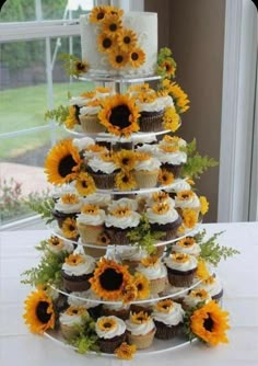 a tiered cake with cupcakes and sunflowers on it