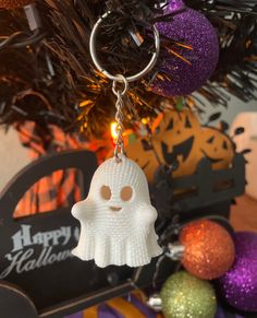 a white ghost keychain hanging from a christmas tree