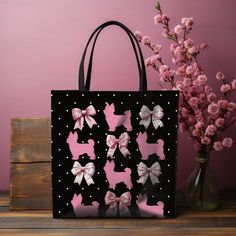 a black bag with pink and white bows on it next to a vase filled with flowers